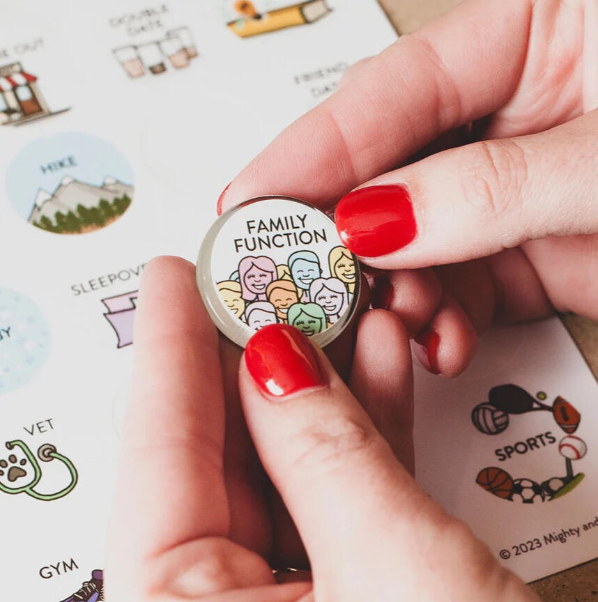 Woman with red nails holds a magnet with a sticker that says "family function" and a drawing of a lot of multicolored people Woman with red nails holds a magnet with a sticker that says "family function" and a drawing of a lot of multicolored people