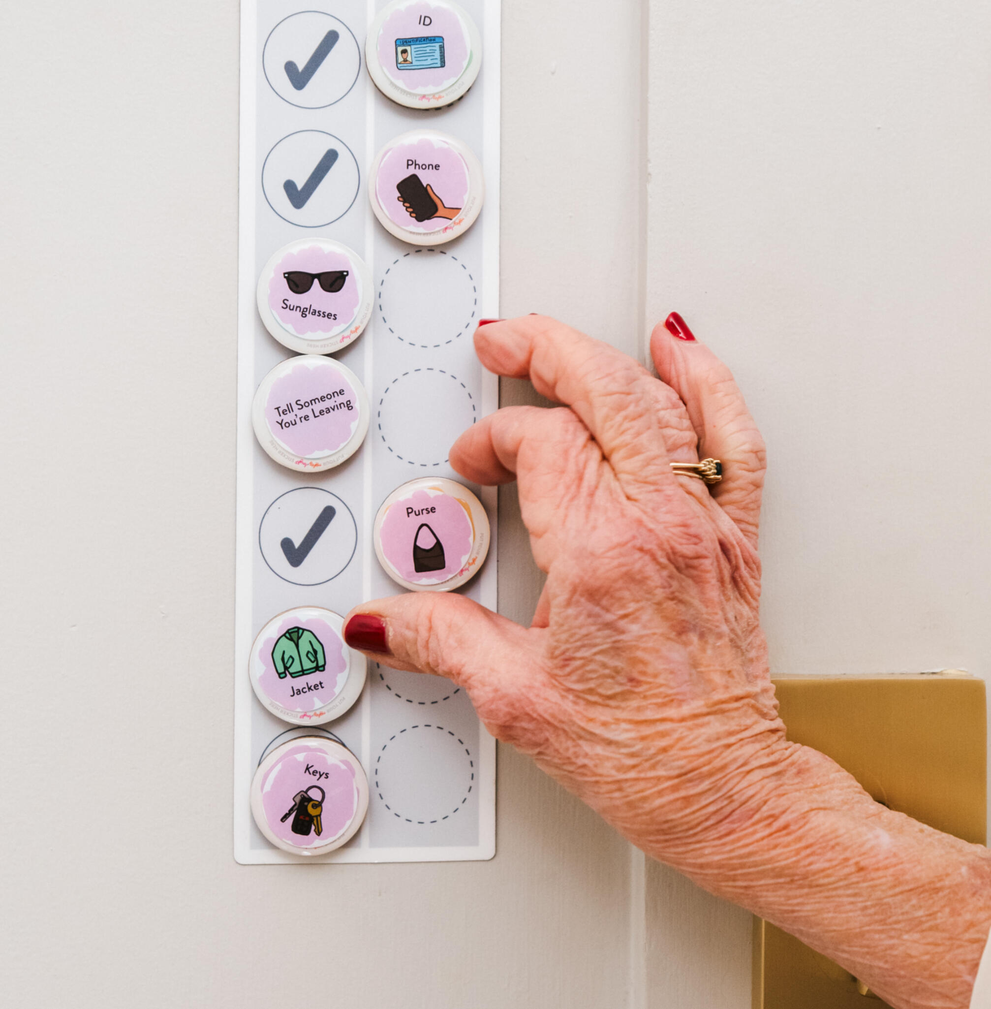 Woman with pink fingernails touches a magnet that has a "move your body" sticker on it as part of the Master To Do List for memo Woman with pink fingernails touches a magnet that has a "move your body" sticker on it as part of the Master To Do List for memory support from Mighty and Bright. Above it is a magnet with the "eat a snack" sticker and below it is a magnet with the sticker